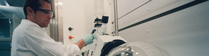 Researcher using scientific equipment wearing safety glasses
